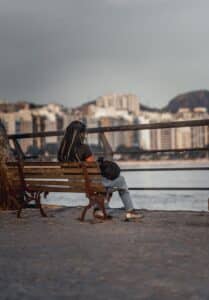 Woman sitting on a bench facing the water in New York City, reflecting calm and resilience after stress therapy in New York City
