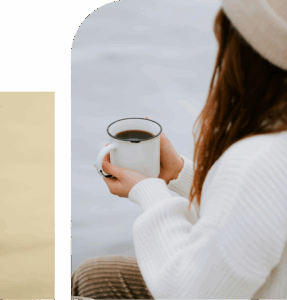Woman holding a cup of coffee in a calm indoor setting, a small everyday moment of comfort and grounding