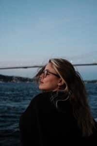 A woman with wind blowing through her hair, standing before the sea, in a peaceful and reflective moment