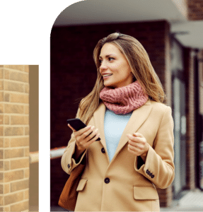 A woman walking out of a building, smiling at her phone, represents forward movement, connection, and daily life.
