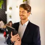 A high-achieving professional holding a folder, smiling after relief from an  anxiety therapist in Midtown Manhattan, NYC