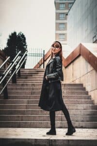 A woman in a leather coat walking up stairs, symbolizing upward movement, effort, and personal progress.