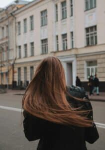 Professionally dressed woman walking alone on city street, representing independence, pressure, and daily life balance