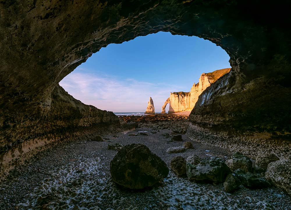 sea cave entrance framing distant cliffs and a natural arch
