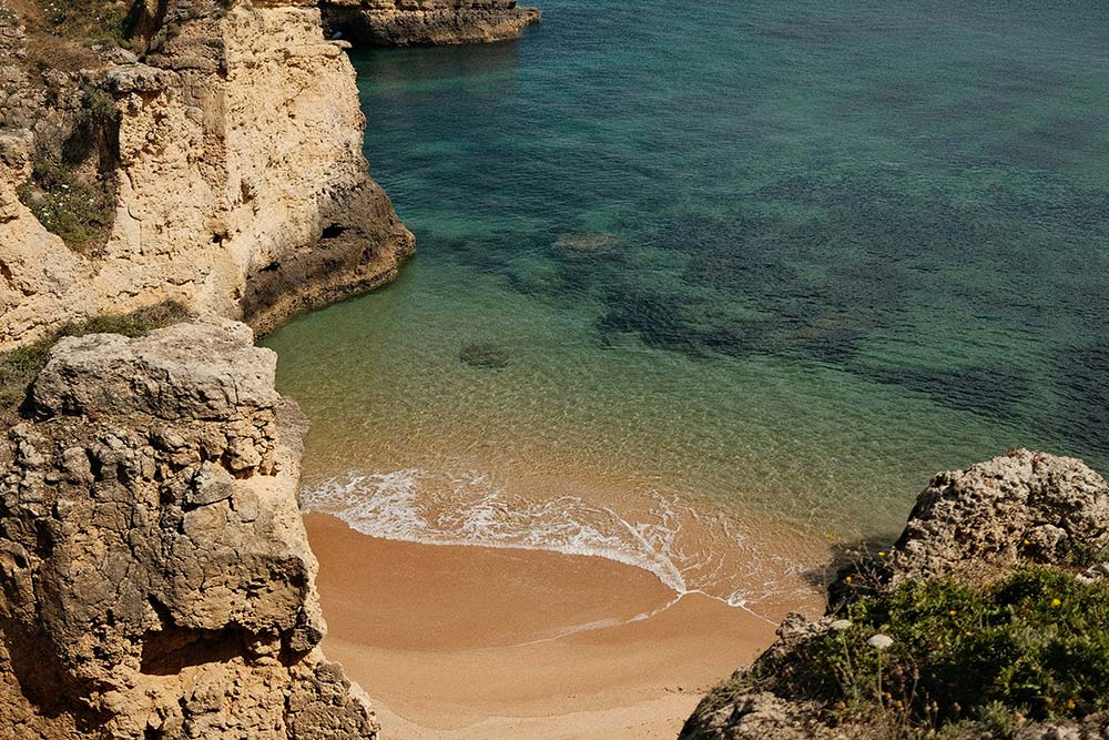 Secluded sandy cove with clear turquoise water and rocky cliffs