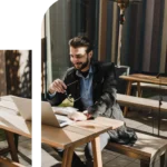A happy male entrepreneur or remote employee working on a laptop at an outdoor café patio table