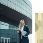 A confident female executive walking outside a modern corporate building holding a laptop and coffee during her morning commute